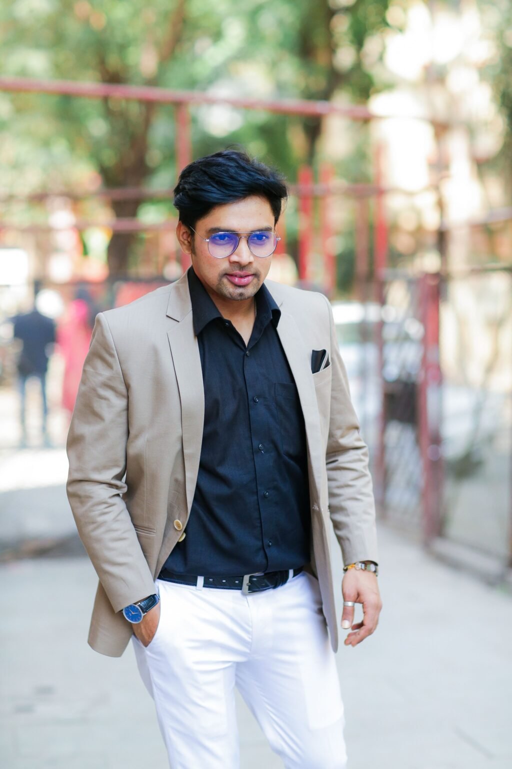 About Trendy man with sunglasses and blazer walking outdoors, showcasing modern fashion in Mumbai.